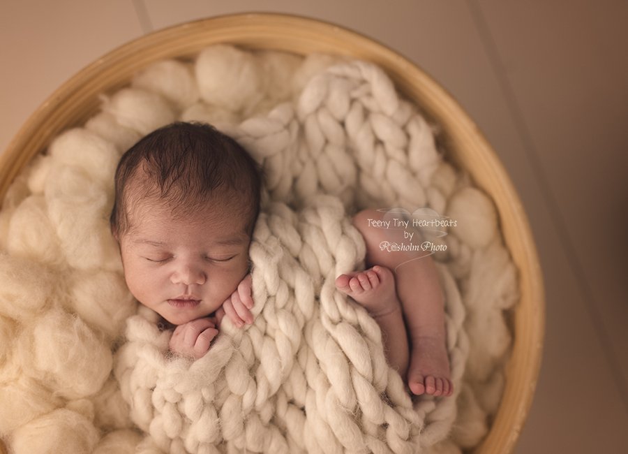 billede af nyfødt med hvidt tæppe omkring sig sovende i kurv