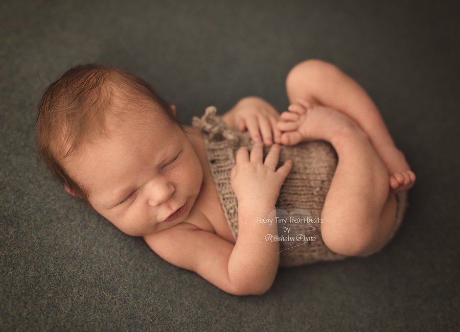 baby dreng poseret på grønt tæppe med lille smil