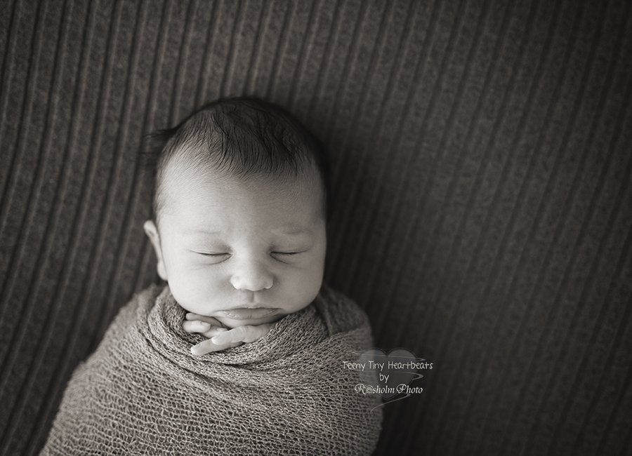 nyfødt dreng pakket ind i tæppe, sovende på tæppe i sort hvid