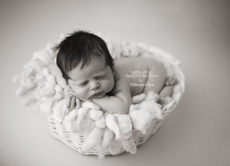 sort hvid billede af sovende nyfødt i hvid kurv
