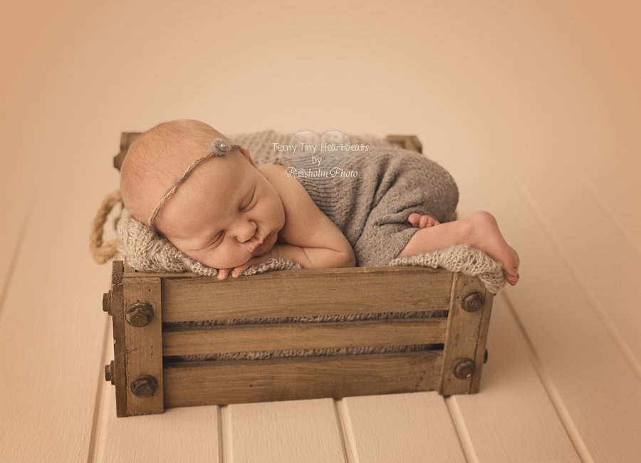 billede af nyfødt sovende i trækasse i grå dragt
