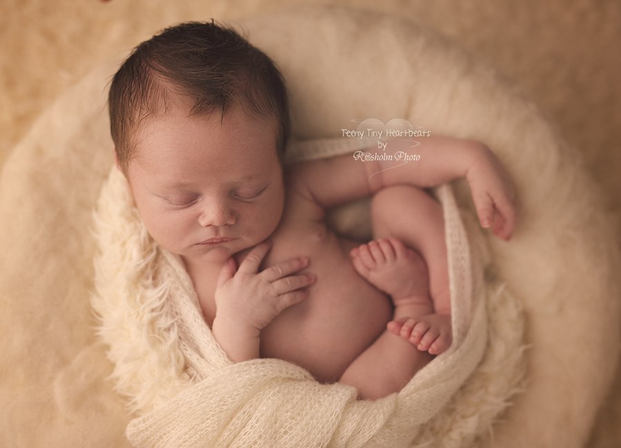 billede af nyfødt dreng sovende i creme farvet tæppe på ryggen