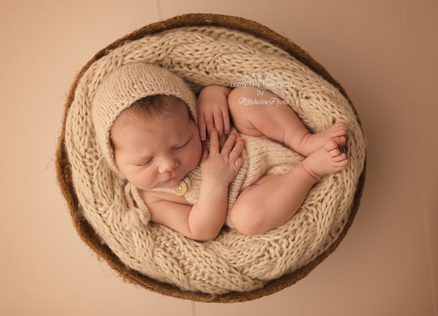 billede af nyfødt fotograferet i kurv med råhvidt tæppe, hue og dragt