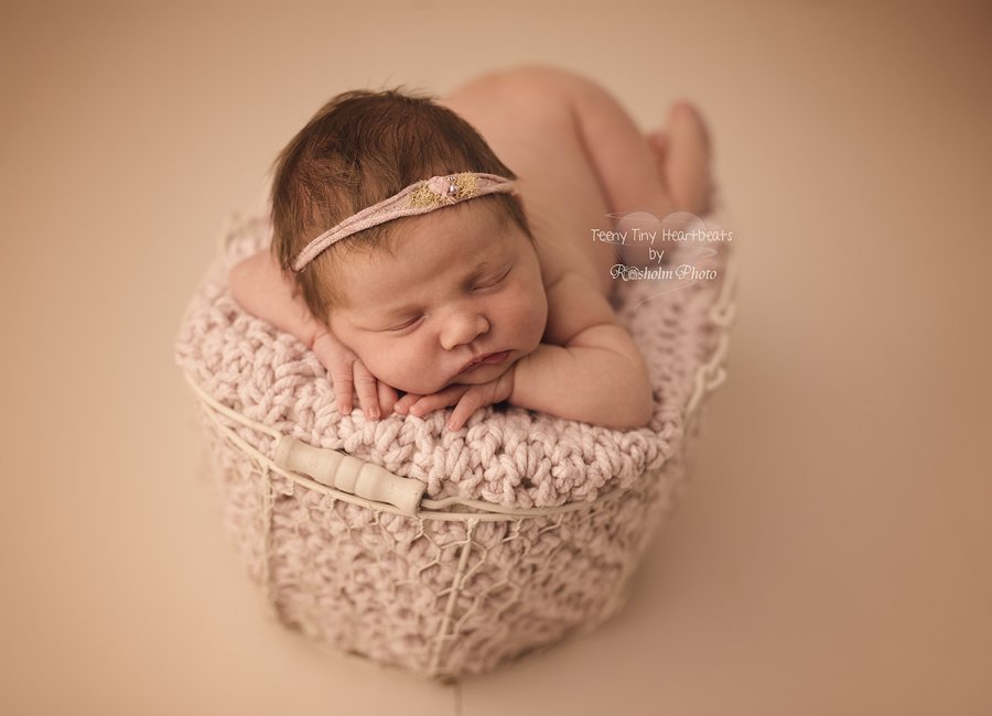nyfødt pige sovende i kurv med lilla tæppe