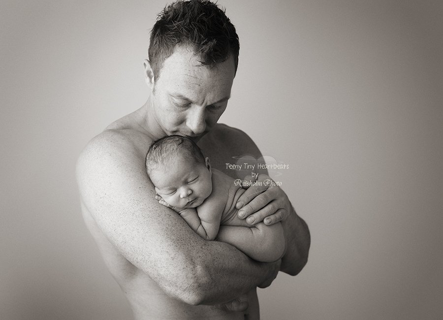 nyfødt sovende på fars arm i sort hvid