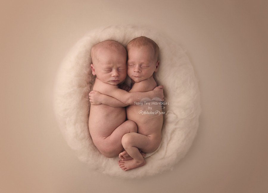 billede af nyfødte tvillinger liggende tæt sammen i creme farvet uldrede