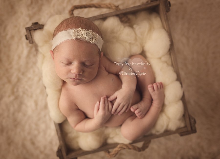 billede af nyfødt pige poseret i hvid uld på ryggen sovende med pandebånd