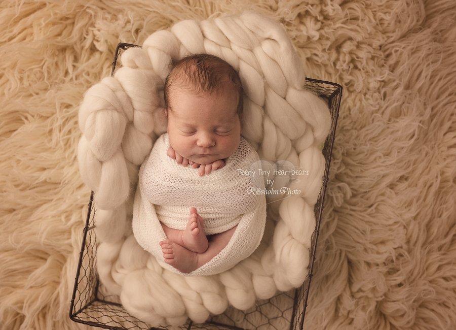 spædbarn sovende i kasse med uldtæppe